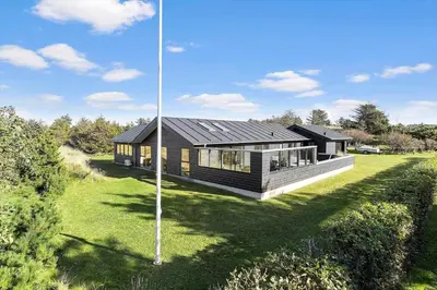 a house with a black roof on a green yard at BL1317-Blokhus-Frederiksensvej-5 in Blokhus