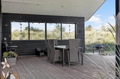 a patio with a table and chairs on a deck at BL1317-Blokhus-Frederiksensvej-5 in Blokhus