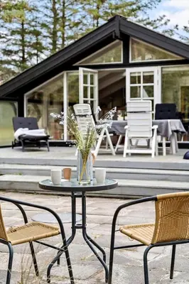 a patio with chairs and a table and a house at BL353-Blokhus-Kragebak-1 in Blokhus