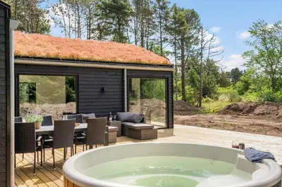 a bath tub sitting on a deck next to a house at BL1465-Blokhus-Bag-Hojen-8-c in Blokhus