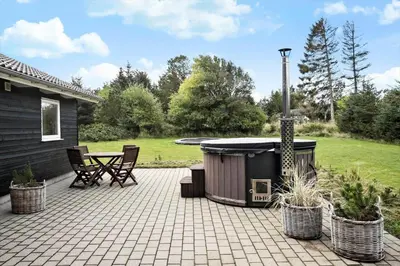 a patio with a hot tub and a table and chairs at BL1785-Blokhus-Jaegerensvej-18 in Blokhus