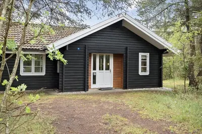 a small black house with a white door at BL1553-Pandrup-Lunekrogen-9 in Pandrup
