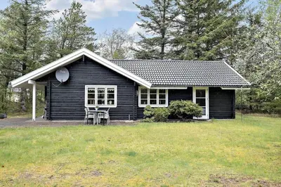 a black house with a chair in front of it at BL1553-Pandrup-Lunekrogen-9 in Pandrup