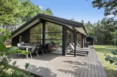 a house with a deck with a table and chairs at BL455-Pandrup-Rodhus-Skolevej-52 in Pandrup