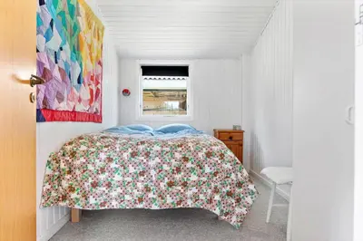 a bedroom with a bed with a floral bedspread and a window at BL1370-Saltum-Fladen-Grund-14 in Saltum