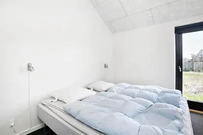 a large bed in a white room with a window at BL400-Blokhus-Sdr-Strandvej-9-B in Blokhus