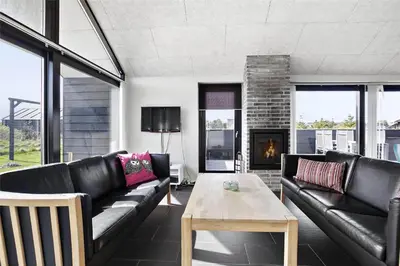 a living room with black leather furniture and a fireplace at BL400-Blokhus-Sdr-Strandvej-9-B in Blokhus