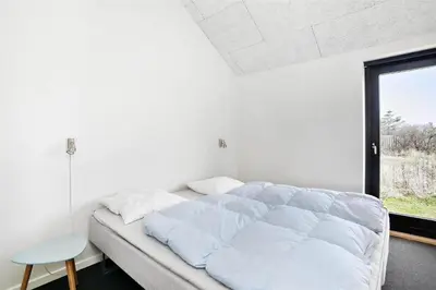 a large bed in a room with a window at BL400-Blokhus-Sdr-Strandvej-9-B in Blokhus