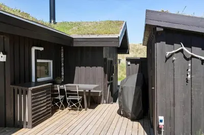 a black house with a table and chairs on a deck at BL1383-Saltum-Foraarsvangen-18 in Saltum