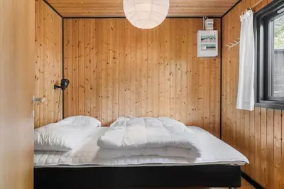 a bedroom with a bed in a wooden wall at BL1208-Saltum-Tippen-10 in Saltum