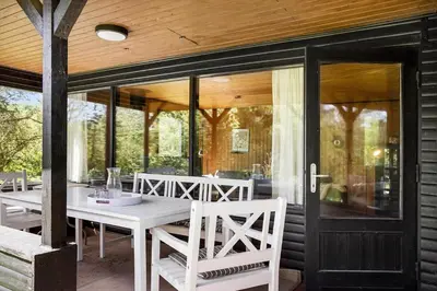 a porch with a white table and chairs and glass doors at BL1208-Saltum-Tippen-10 in Saltum