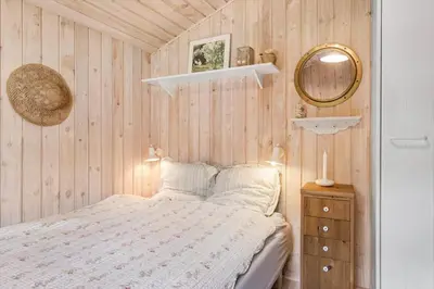 a small bedroom with a bed and a mirror at BL812-Blokhus-Morten-Nielsensvej-10 in Blokhus