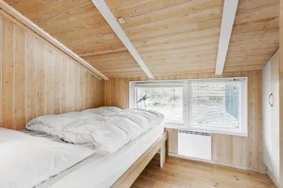 a bed in a room with a wooden ceiling at BL161-Saltum-Taarnfalkevej-16 in Saltum