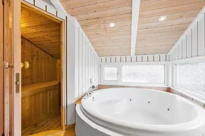 a large white tub in a bathroom with a wooden ceiling at BL161-Saltum-Taarnfalkevej-16 in Saltum
