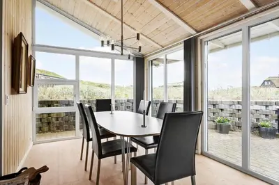 a dining room with a table and chairs and windows at BL161-Saltum-Taarnfalkevej-16 in Saltum