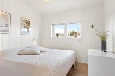 a white bedroom with a bed and two windows at BL1403-Blokhus-Sorensensvej-7 in Blokhus
