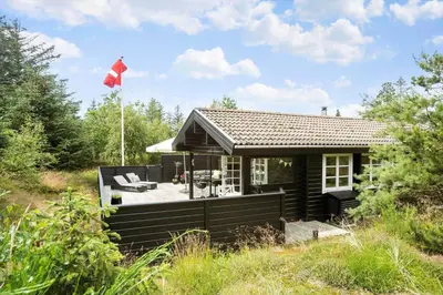 a small black house with a flag on it at BL1610-Blokhus-Soren-Petersvej-20 in Blokhus