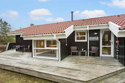 a house with a wooden deck with chairs on it at BL1259-Blokhus-Bag-Hojen-83 in Blokhus