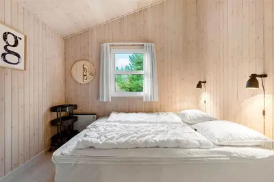 a bedroom with a white bed and a window at BL1259-Blokhus-Bag-Hojen-83 in Blokhus