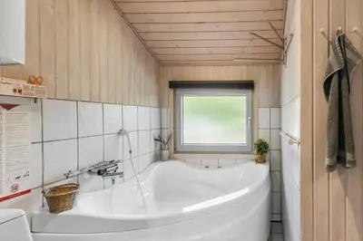 a large white tub in a bathroom with a window at BL256-Blokhus-Skytten-35 in Blokhus