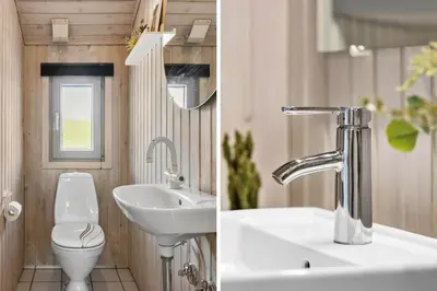 a bathroom with a sink and a toilet and a mirror at BL256-Blokhus-Skytten-35 in Blokhus