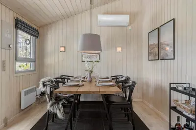 a dining room with a table with chairs and a lamp at BL256-Blokhus-Skytten-35 in Blokhus