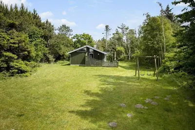 a small shed in a grassy field with a goal at BL433-Blokhus-Raappenmark-8 in Blokhus