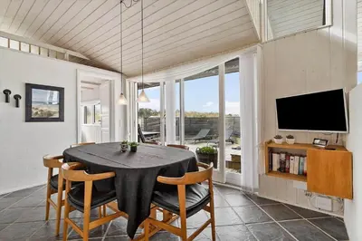 a dining room with a table and chairs and a tv at BL168-Saltum-Taarnfalkevej-11 in Saltum