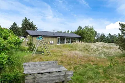 a wooden bench in front of a house at BL173-Blokhus-Bloksbjerg-88 in Blokhus