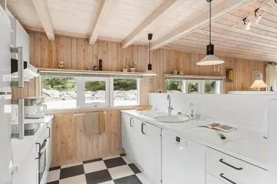 a kitchen with white counters and wooden walls and windows at BL1202-Saltum-Revlingevej-6 in Saltum