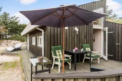 a table and chairs with an umbrella on a deck at BL1202-Saltum-Revlingevej-6 in Saltum