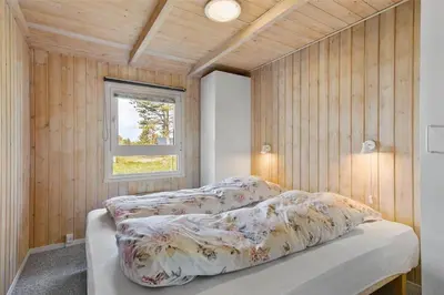 a bedroom with a bed in a room with wood walls at BL1624-Blokhus-Jaegerbakken-1 in Blokhus