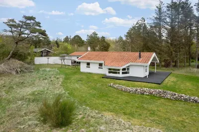 a white house with a red roof in a yard at BL1624-Blokhus-Jaegerbakken-1 in Blokhus
