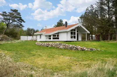 a white house with a pile of rocks at BL1624-Blokhus-Jaegerbakken-1 in Blokhus