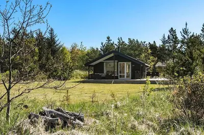 a small black house in the middle of a field at BL1272-Pandrup-Kirkekrogen-7 in Pandrup