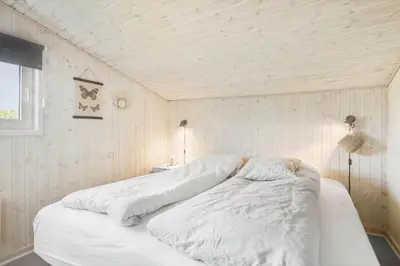a large white bed in a room with wooden walls at BL123-Blokhus-Nonnestien-8 in Blokhus