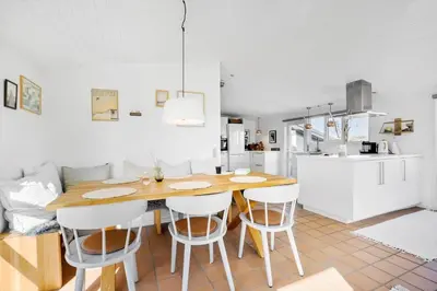 a kitchen and dining room with a wooden table and chairs at BL123-Blokhus-Nonnestien-8 in Blokhus