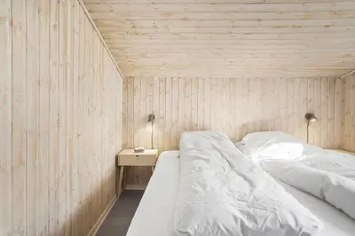 a bedroom with a bed in a wooden wall at BL123-Blokhus-Nonnestien-8 in Blokhus