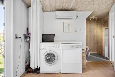 a washer and dryer in a laundry room with a door at BL123-Blokhus-Nonnestien-8 in Blokhus