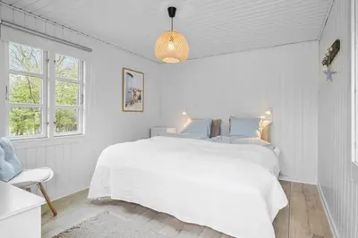a white bedroom with a white bed and a window at BL1280-Blokhus-Bloksbjerg-50 in Blokhus