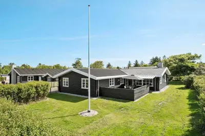 a house with a flag pole in the yard at BL1284-Blokhus-Tyttebaervej-4 in Blokhus