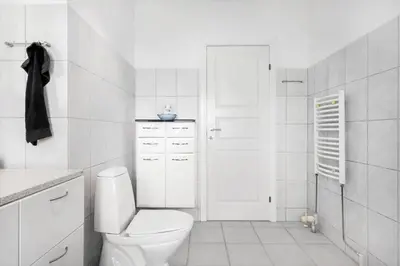 a white bathroom with a toilet and a door at BL1284-Blokhus-Tyttebaervej-4 in Blokhus