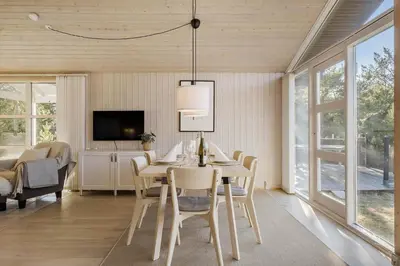 a dining room with a table and chairs and a tv at BL1458-Blokhus-Lyngmarken-6 in Blokhus