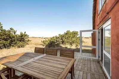 a wooden table and bench on a deck with a window at BL1249-Pandrup-Rodhus-Klitvej-80 in Pandrup