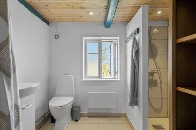 a white bathroom with a toilet and a window at BL1249-Pandrup-Rodhus-Klitvej-80 in Pandrup