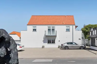 a white house with a car parked in front of it at BL1287-Blokhus-Klitgaardsvej-3-A-1-2 in Blokhus