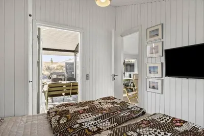 a bedroom with a bed and a television and a balcony at BL1173-20-Pandrup-Hunetorp-Klitvej-119 in Pandrup