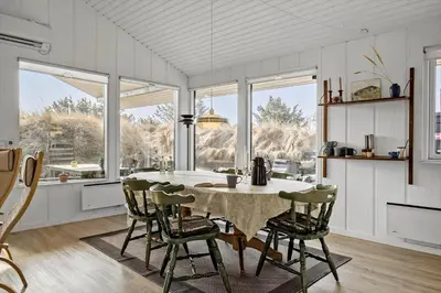 a kitchen with a table and chairs and windows at BL1173-20-Pandrup-Hunetorp-Klitvej-119 in Pandrup