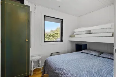 a small bedroom with a bed and a window at BL1101-Pandrup-Rodhusparken-56 in Pandrup