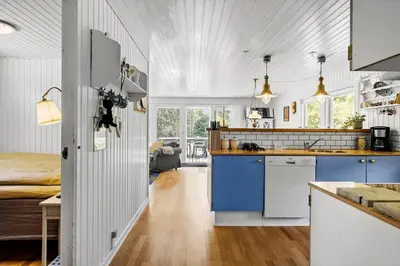 a kitchen with blue cabinets and a room with a bed at BL1101-Pandrup-Rodhusparken-56 in Pandrup